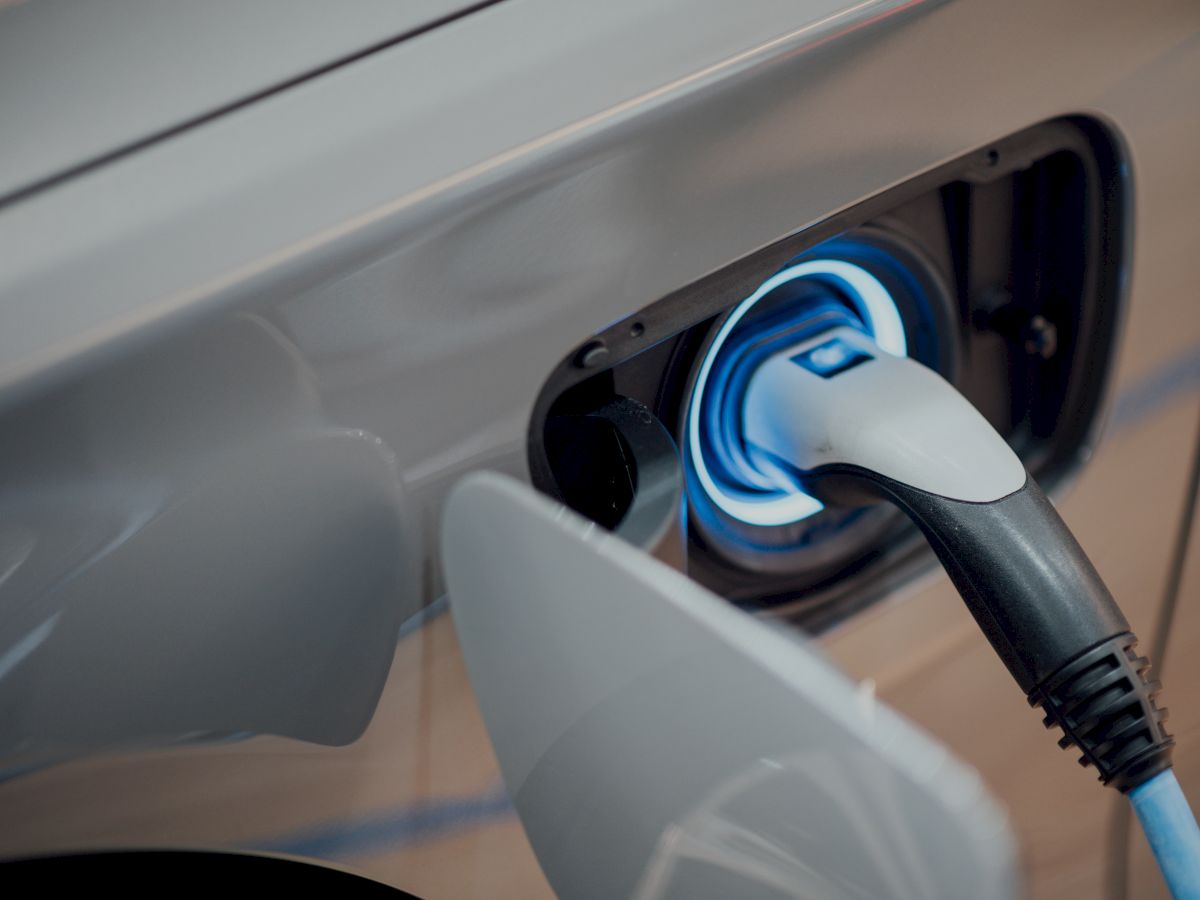 An electric car is shown being charged, with a charging plug connected to its port.