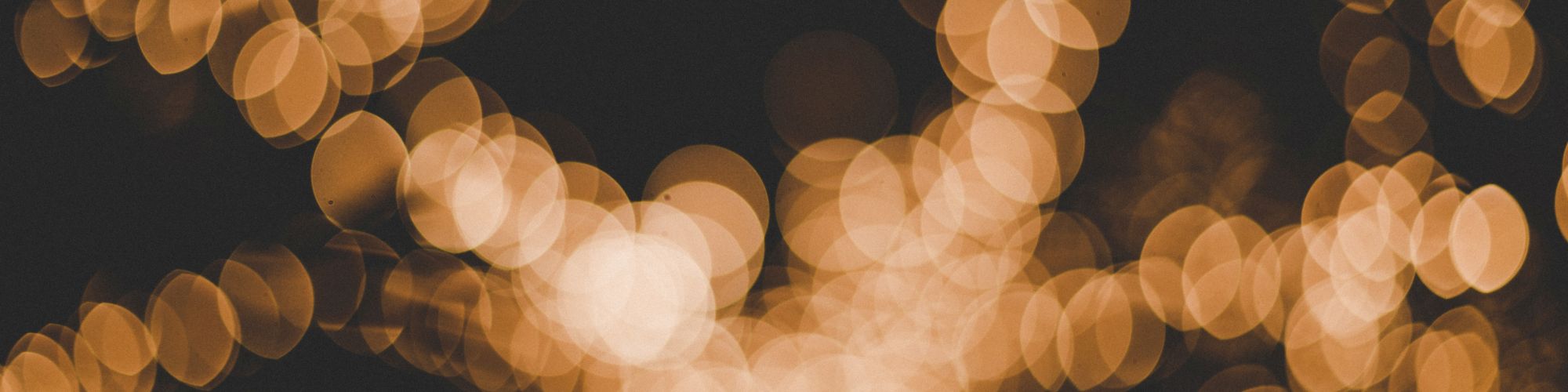 This image shows a blurred background of warm, golden bokeh lights, creating an abstract and festive visual effect.